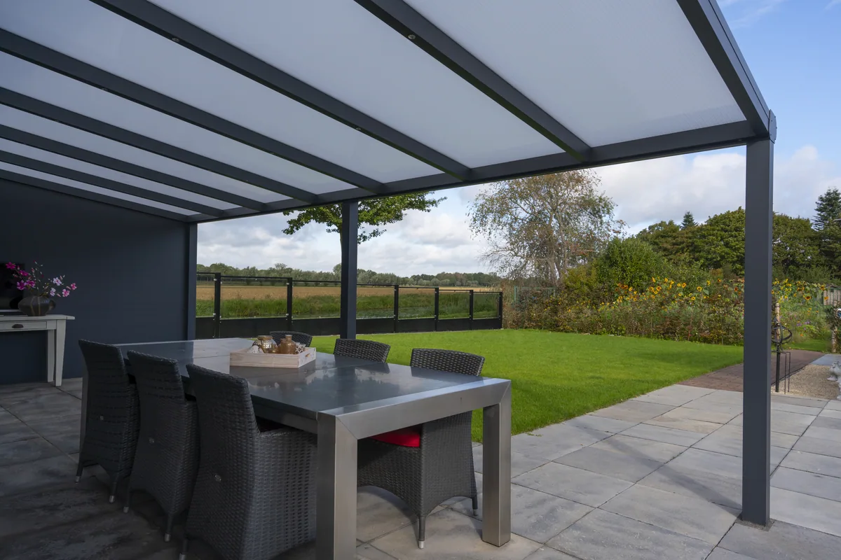 Dining table beneath a Bosco veranda looking onto a lawn